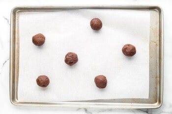 brownie cookie dough balls on a parchment paper lined baking sheet