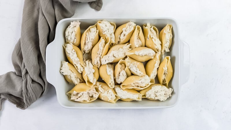 chicken alfredo stuffed pasta shells in a white baking dish before baking