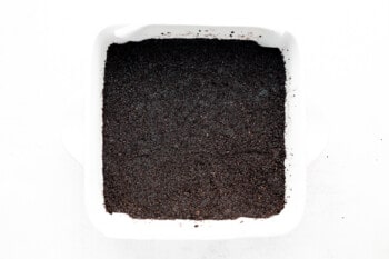 Oreo cookie crust in a white square baking pan