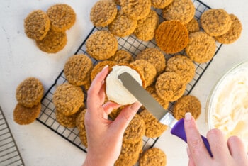 hand using an offset spatula to spread filling onto bottom cookie for oatmeal cream pies