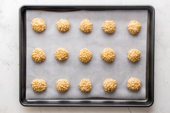 pignoli cookie dough balls on a parchment lined baking sheet before baking