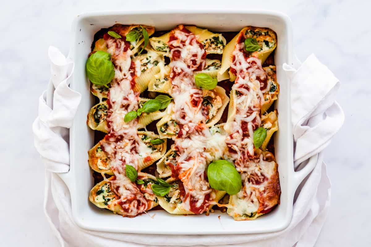 stuffed shells with spinach in a casserole dish with basil.
