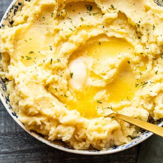 mashed potatoes in a bowl with butter on top with a spoon