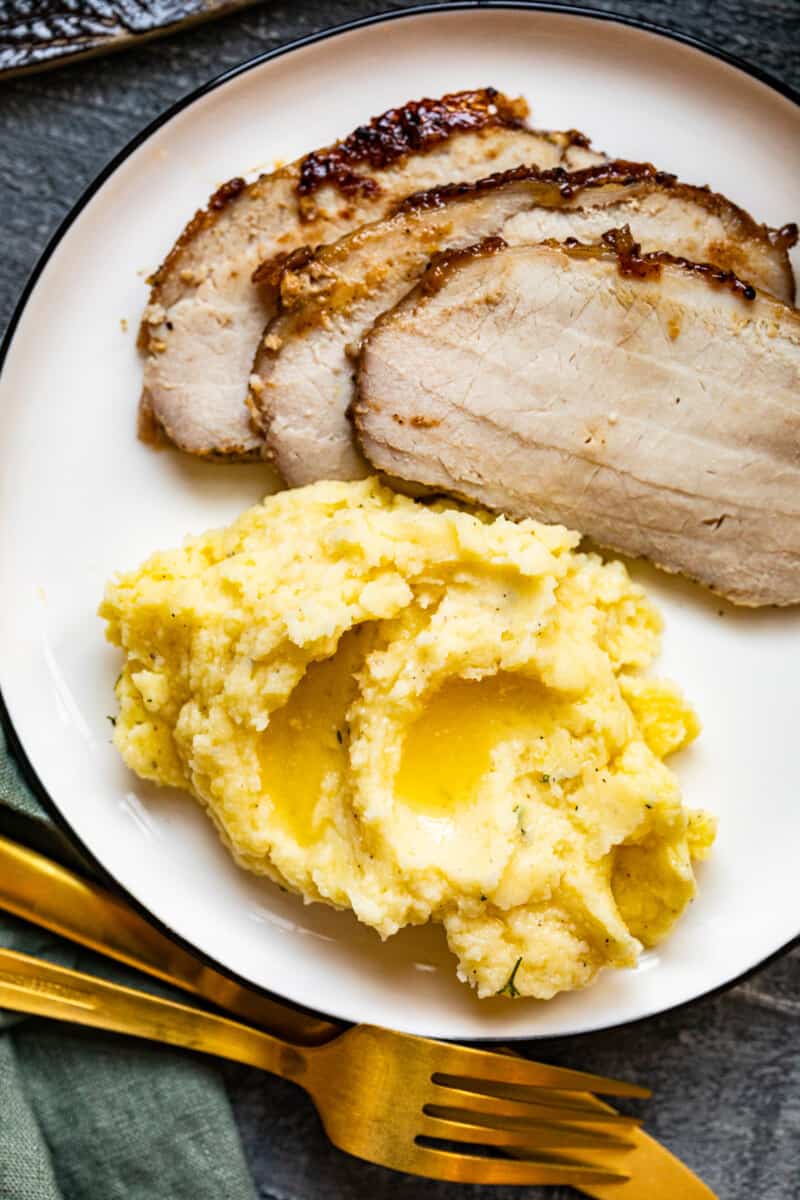 mashed potatoes and sliced pork tenderloin on a white plate