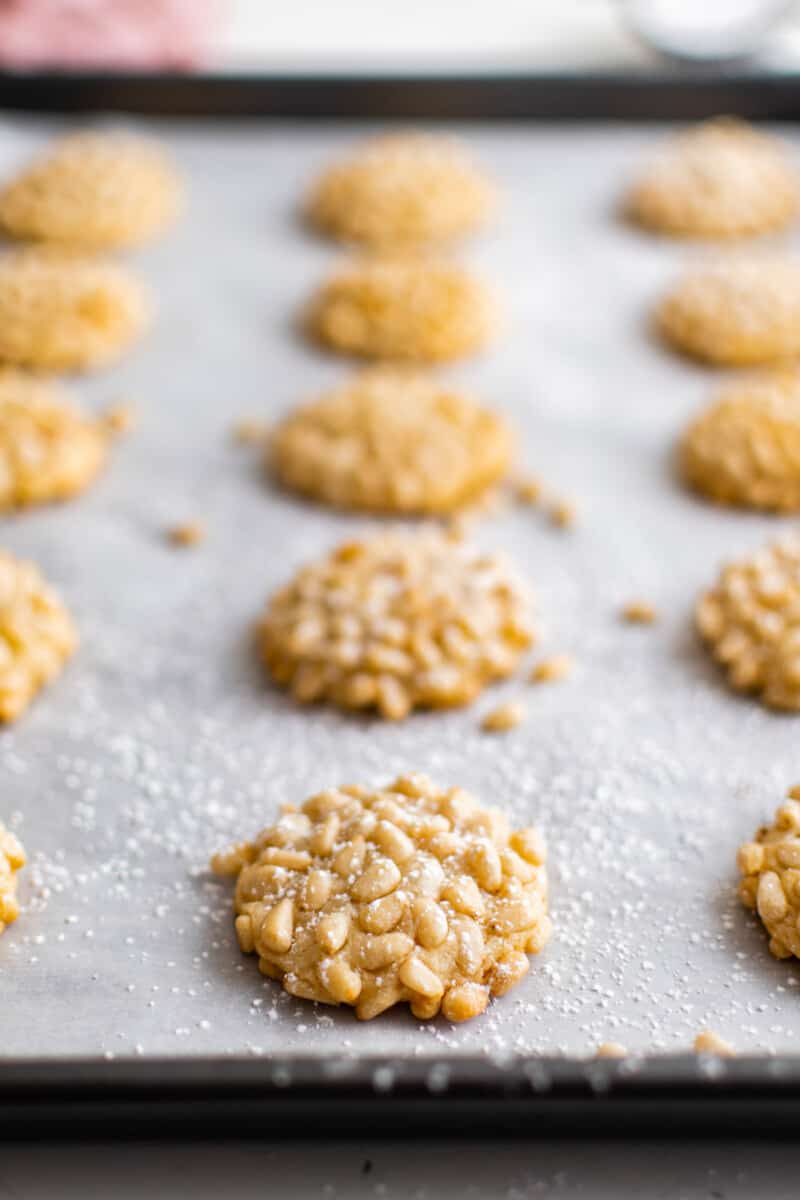 pignoli cookies after baking on a parchment lined baking sheet