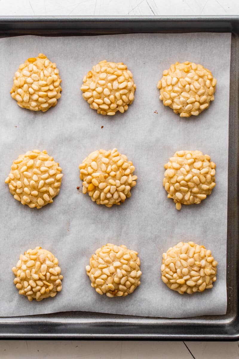 9 pignoli cookies on a parchment paper lined baking sheet