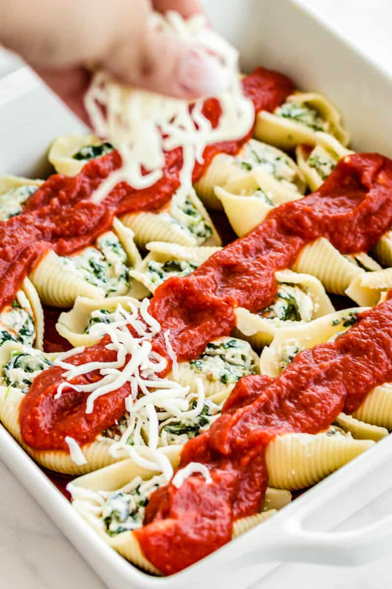 sprinkling cheese on spinach stuffed shells