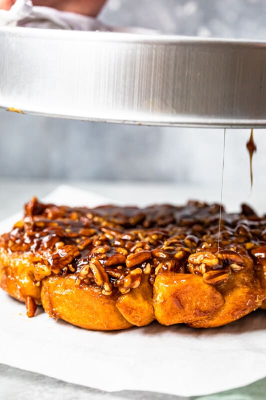 hands inverting sticky buns from the baking pan onto a white serving tray