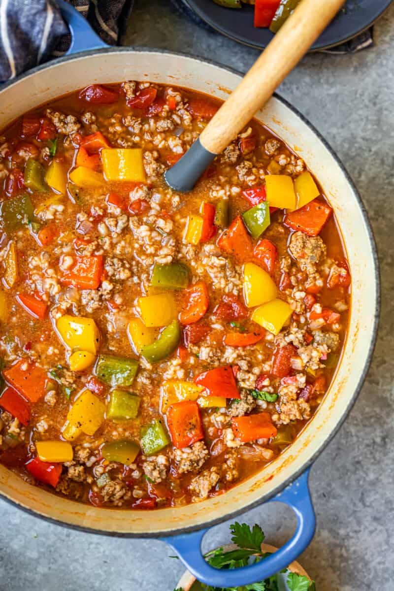 stuffed pepper soup in a blue dutch oven with a wood spoon