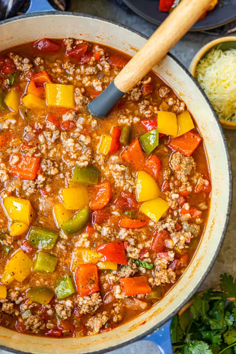 stuffed pepper soup in a blue dutch oven with a wood spoon