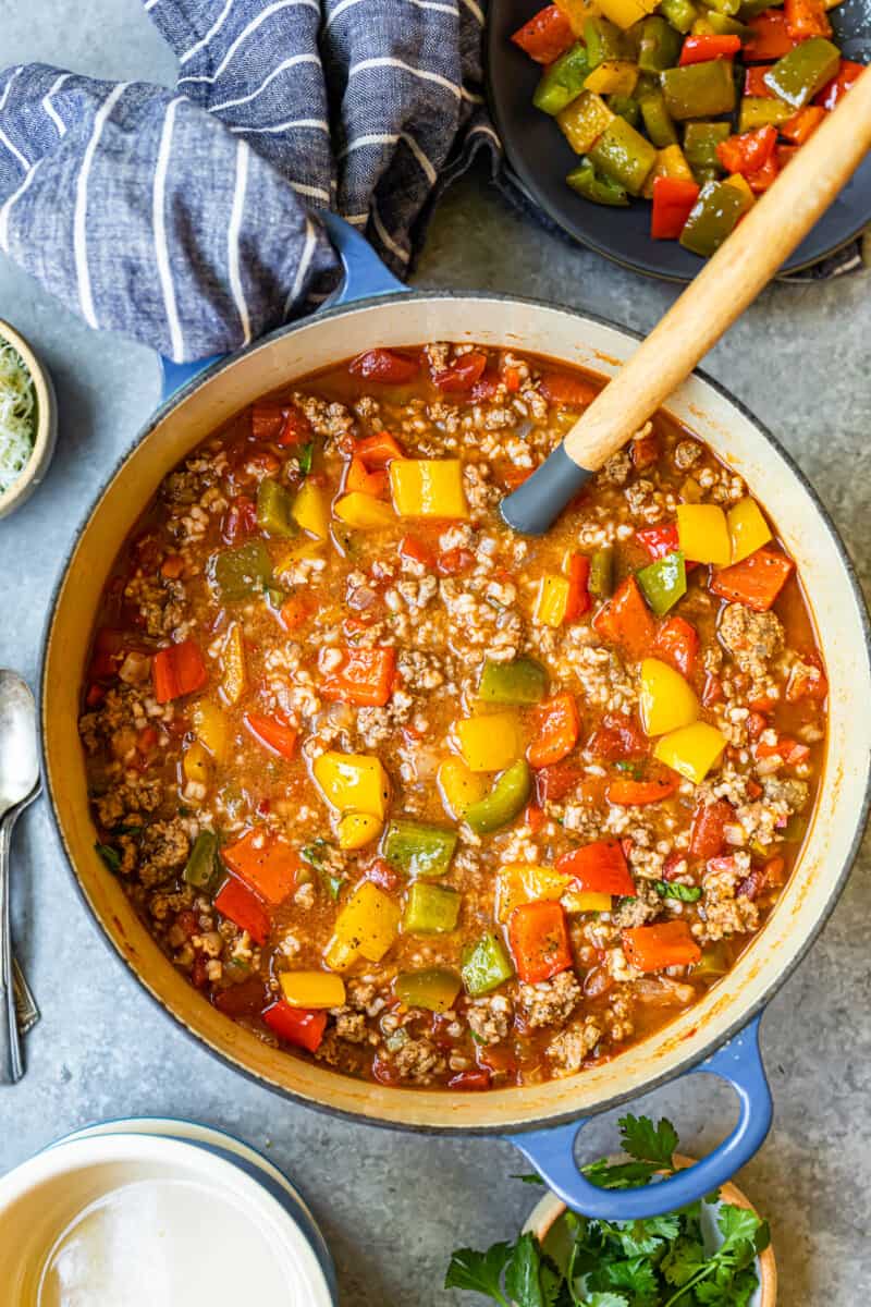 stuffed pepper soup in a blue dutch oven with a wood spoon