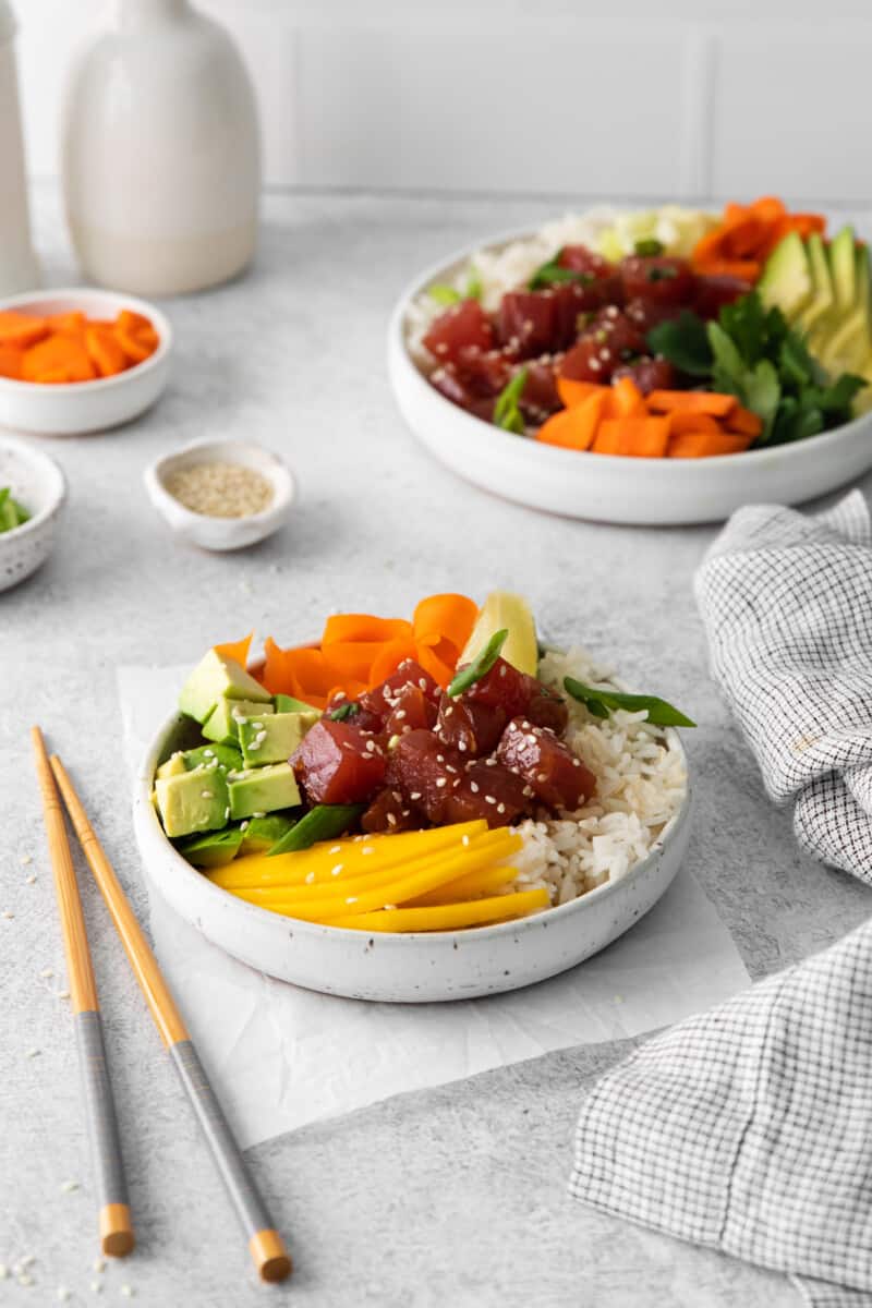 tuna poke bowl in a white bowl with chopsticks.