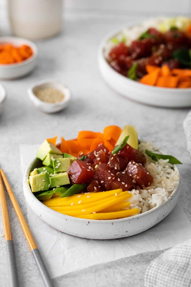 tuna poke bowl in a white bowl with chopsticks.