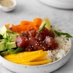 tuna poke bowl in a white bowl with chopsticks.