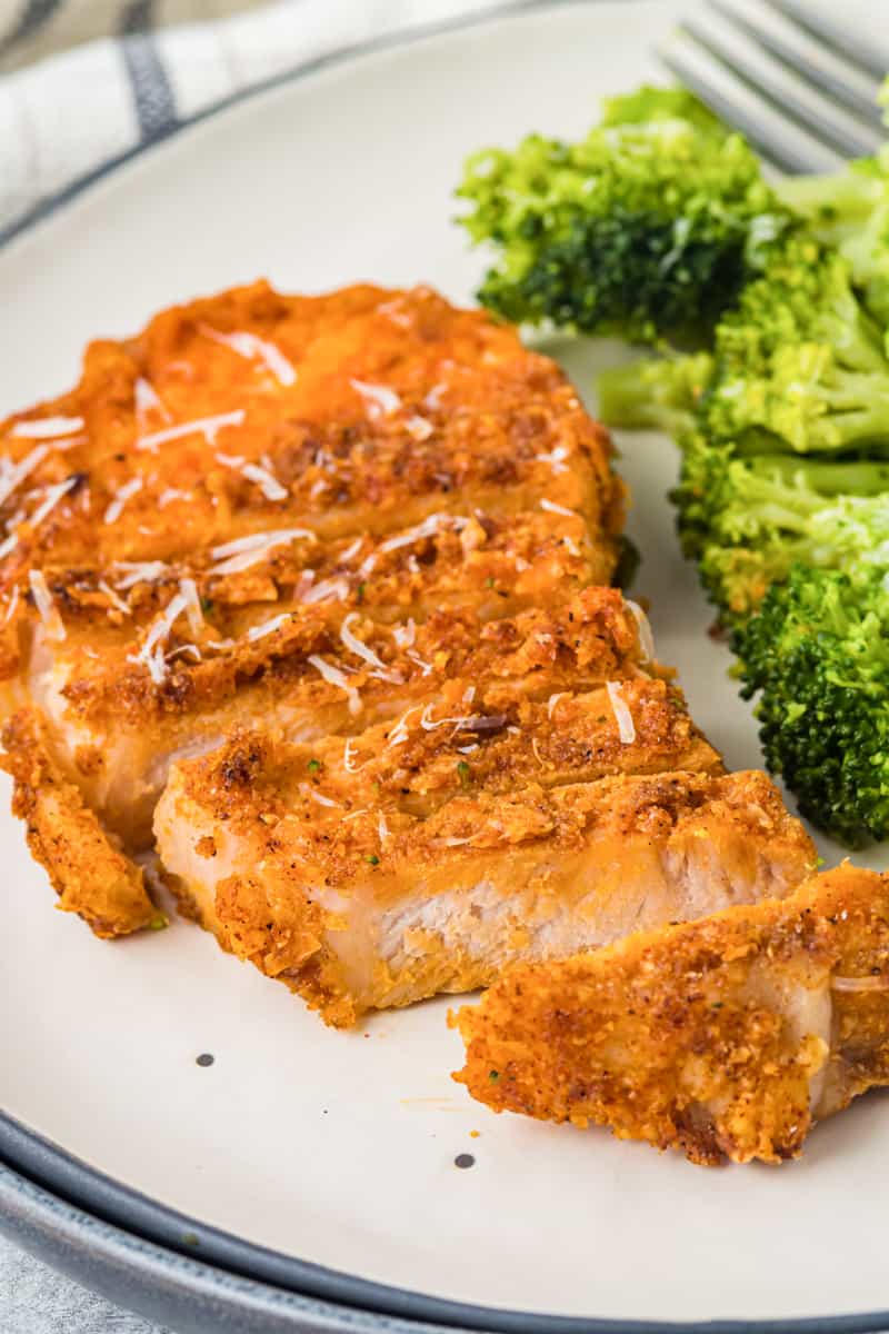 sliced pork chop on a white plate with broccoli