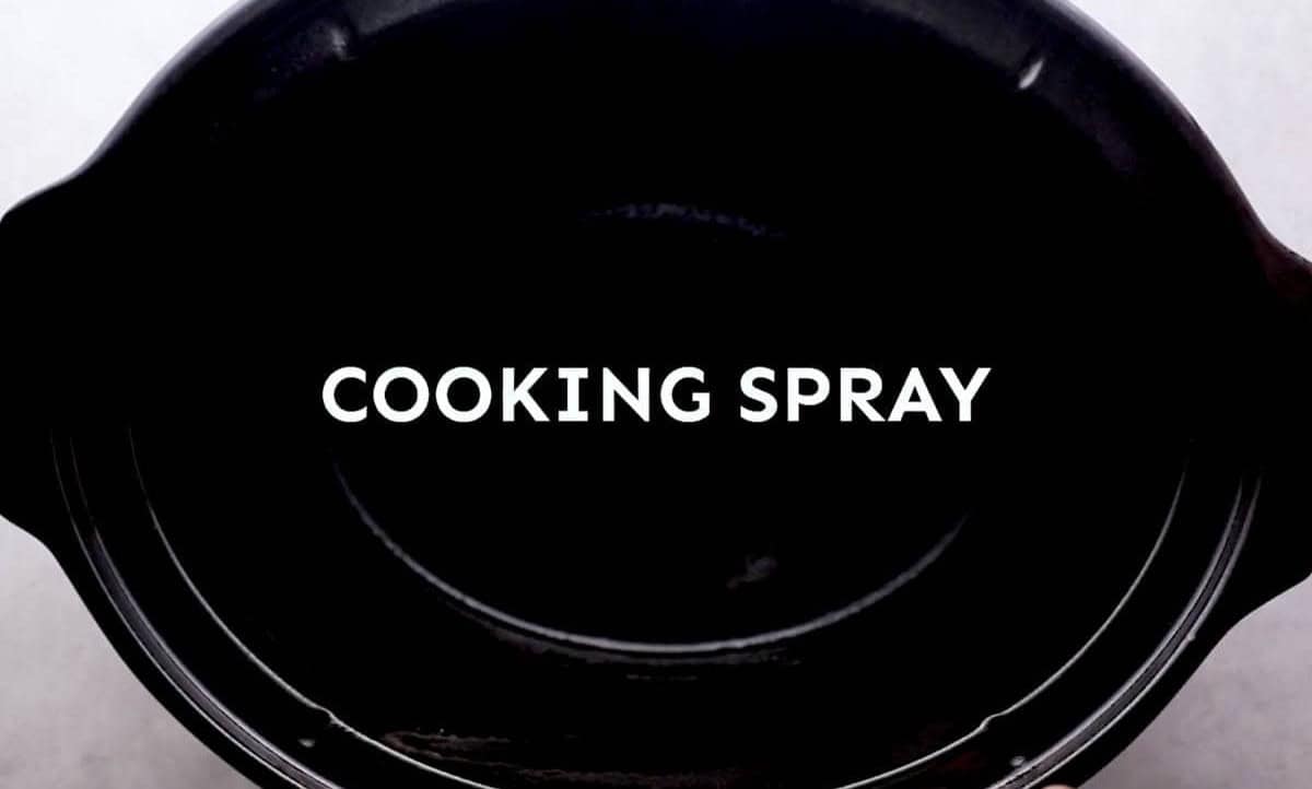 A black crockpot with a message to spray with cooking spray.
