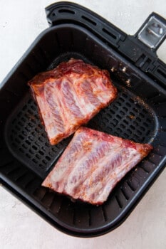 ribs in an air fryer basket before cooking