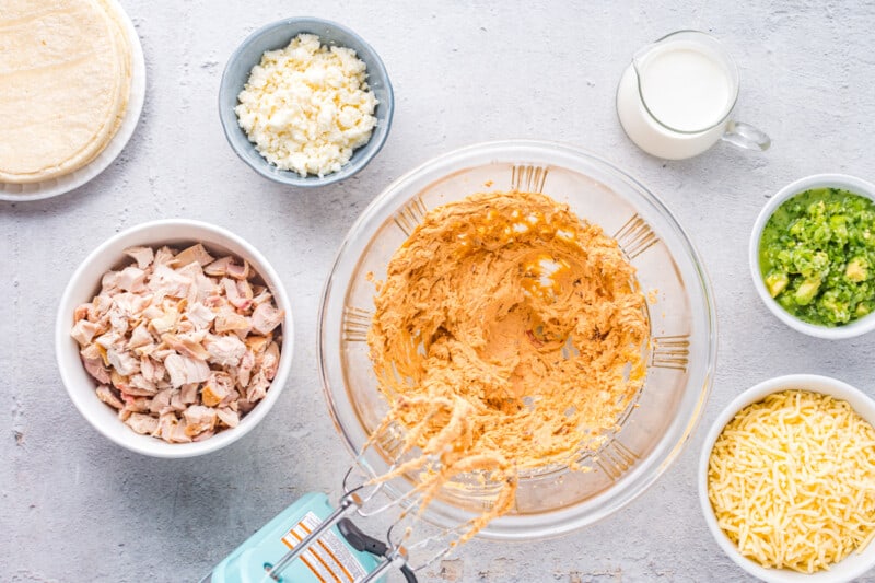 chicken taquito filling in a glass bowl with a hand mixer