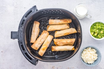 chicken taquitos in air fryer basket after cooking