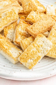 close up of pan fried tofu on a white plate.