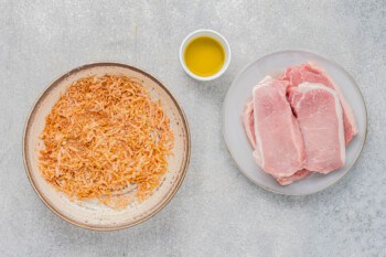 seasoning mixture in a bowl, olive oil in a small bowl, and pork chops on a plate