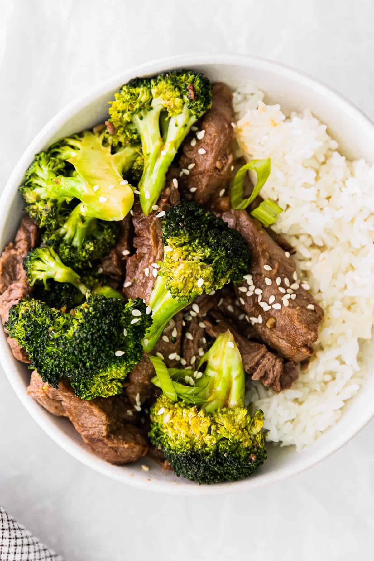 overhead image of beef and broccoli with rice in a white bowl