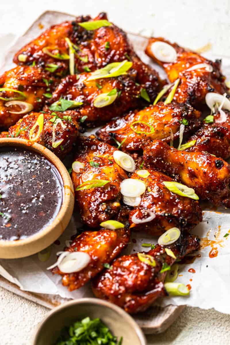 baked korean hot wings on a serving platter with sauce in a bowl