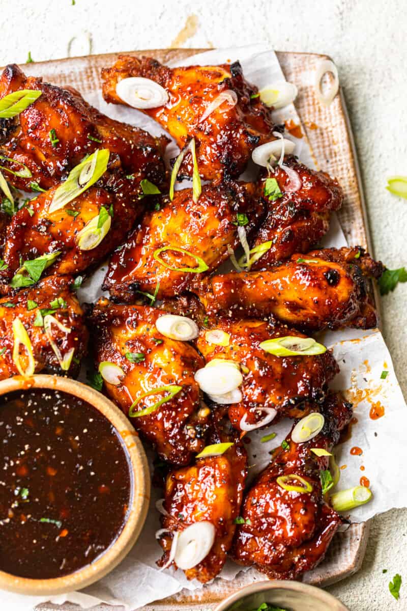 baked korean hot wings on a serving platter with sauce in a bowl