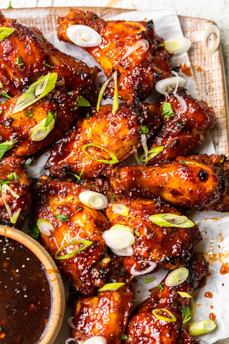 baked korean hot wings on a serving platter with sauce in a bowl