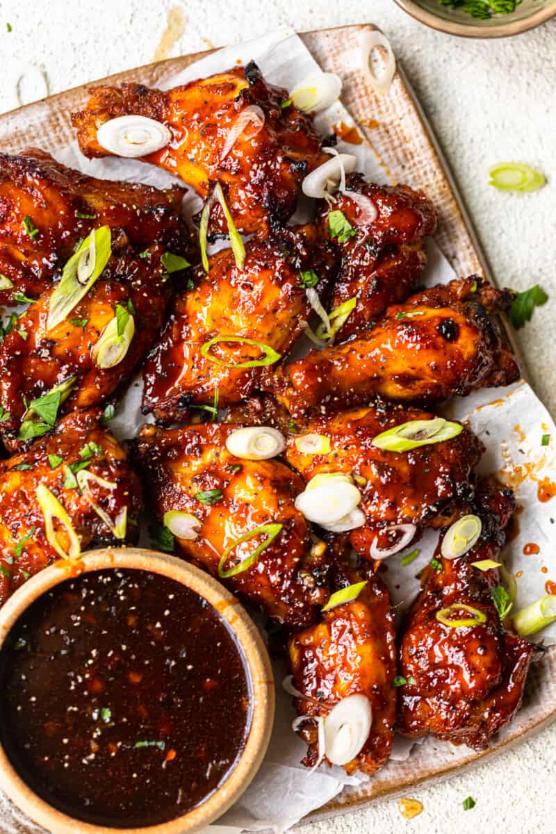 baked korean hot wings on a serving platter with sauce in a bowl