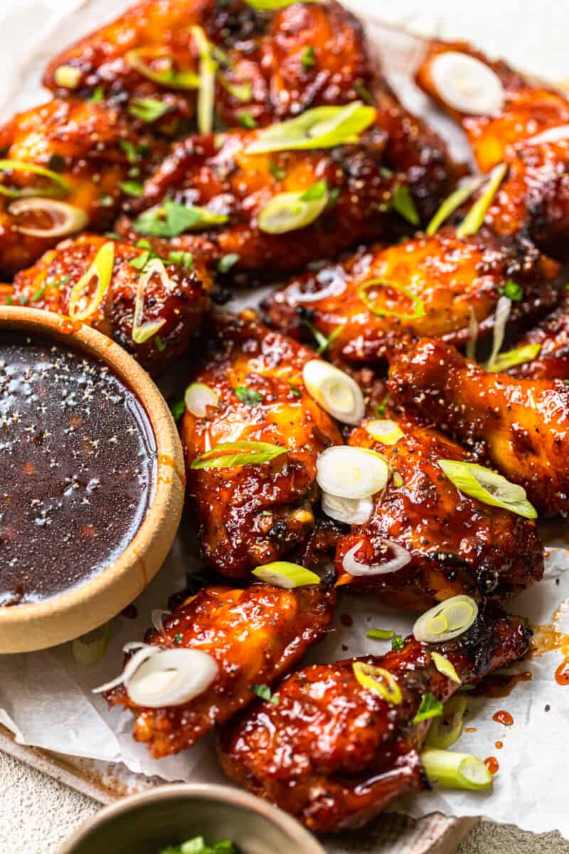 baked korean hot wings on a serving platter with sauce in a bowl