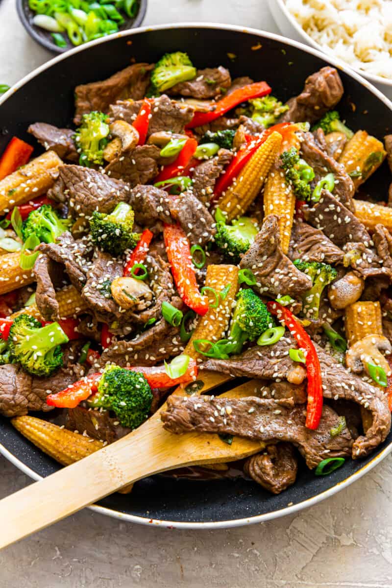 beef stir fry in a wok with a wood spoon