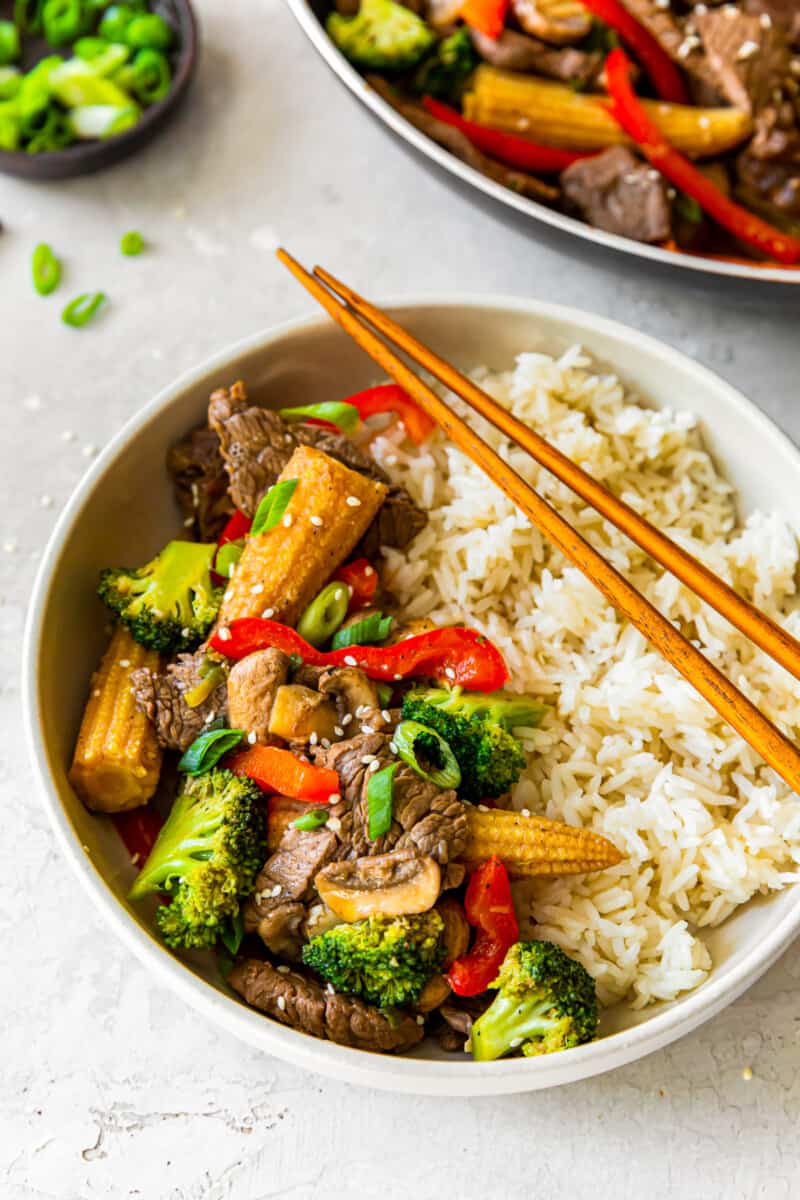 beef stir fry and rice in a bowl with chopsticks