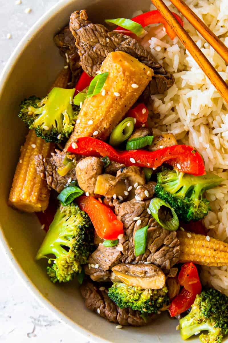 beef stir fry and rice in a bowl with chopsticks