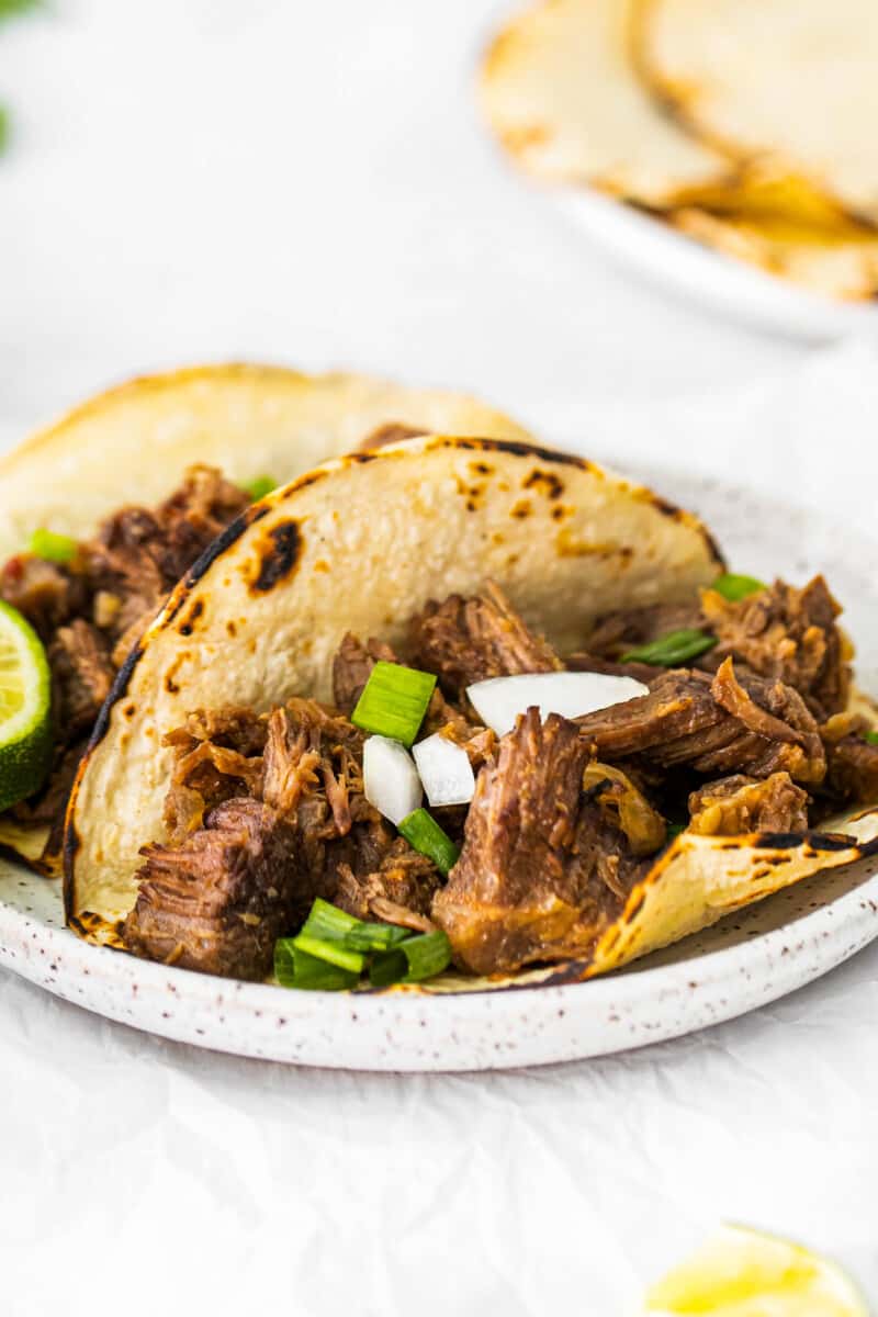 2 beef carnitas tacos on a white plate