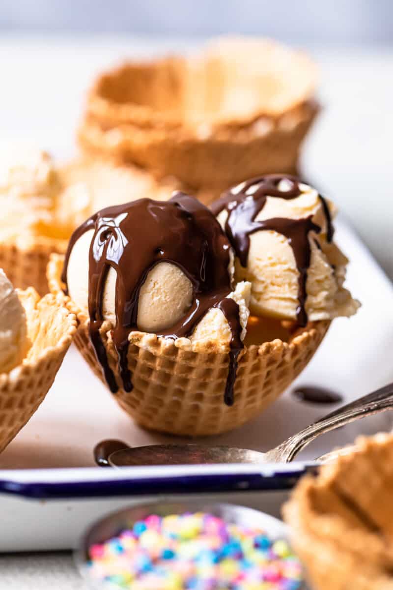 2 scoops of ice cream in a waffle cone bowl topped with chocolate magic shell