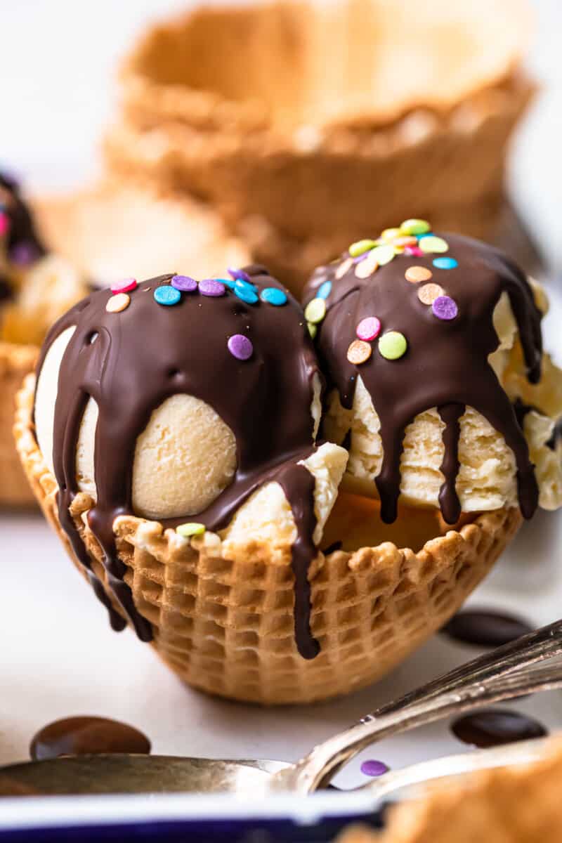 2 scoops of ice cream in a waffle cone bowl topped with chocolate magic shell