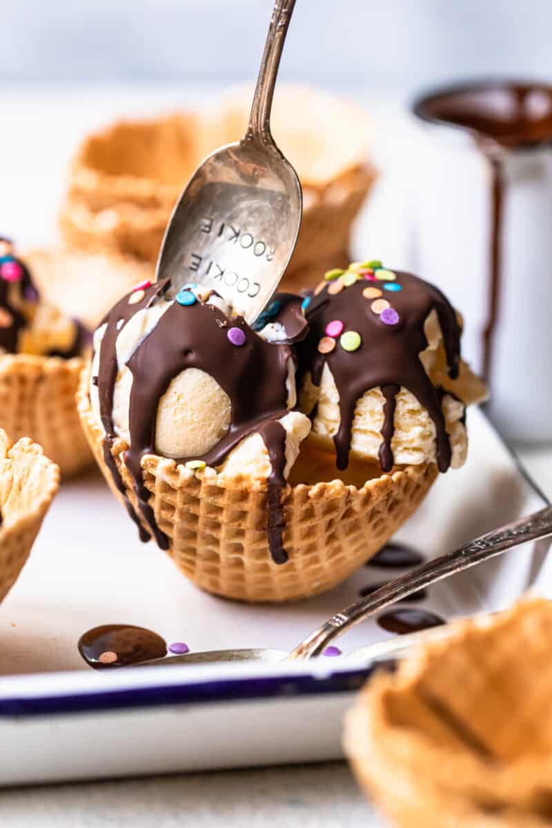 spoon in a waffle cone bowl of ice cream topped with chocolate magic shell