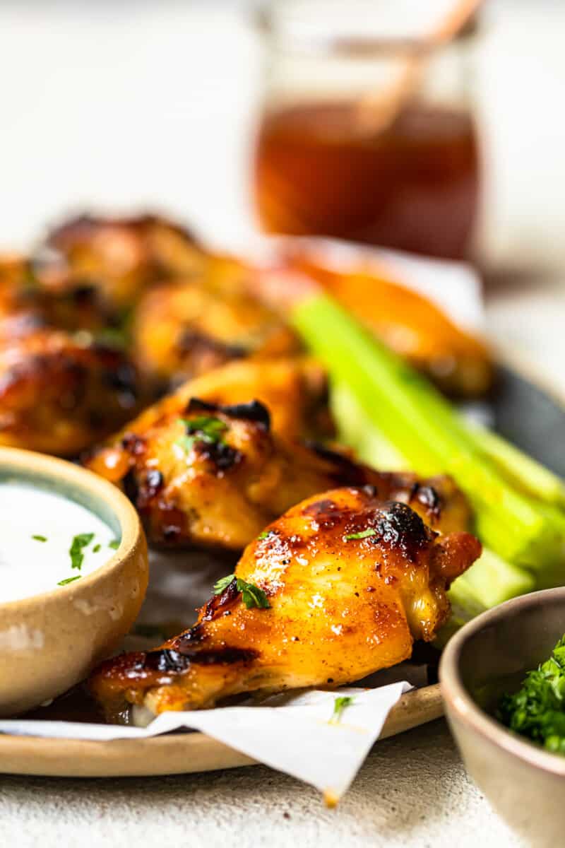 hot honey chicken wings and celery slices on a serving tray with ranch dip in a small bowl