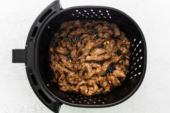 cooked steak slices in an air fryer basket