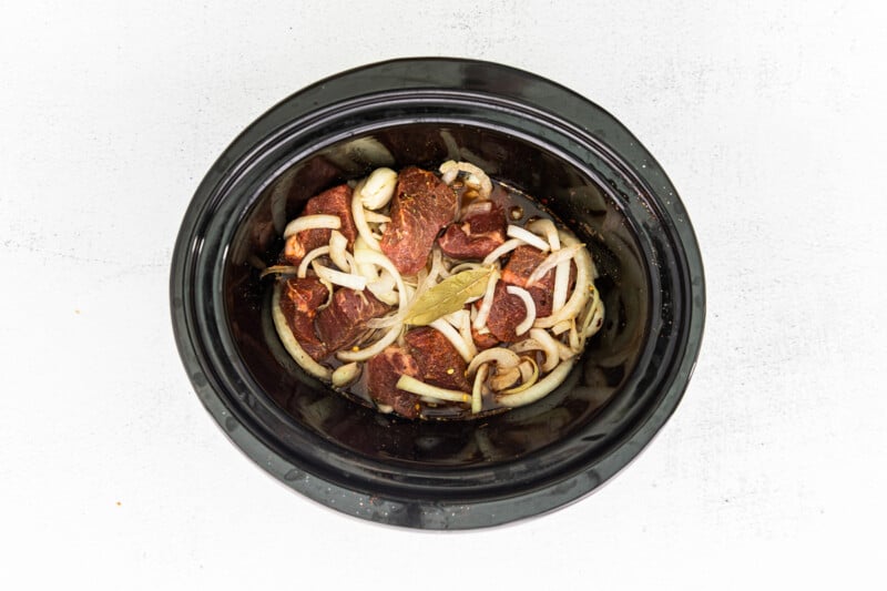 beef, onions, and spices in a crockpot
