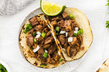 2 beef carnitas tacos on a white plate