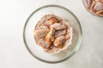 chicken wings in flour mixture in a glass bowl