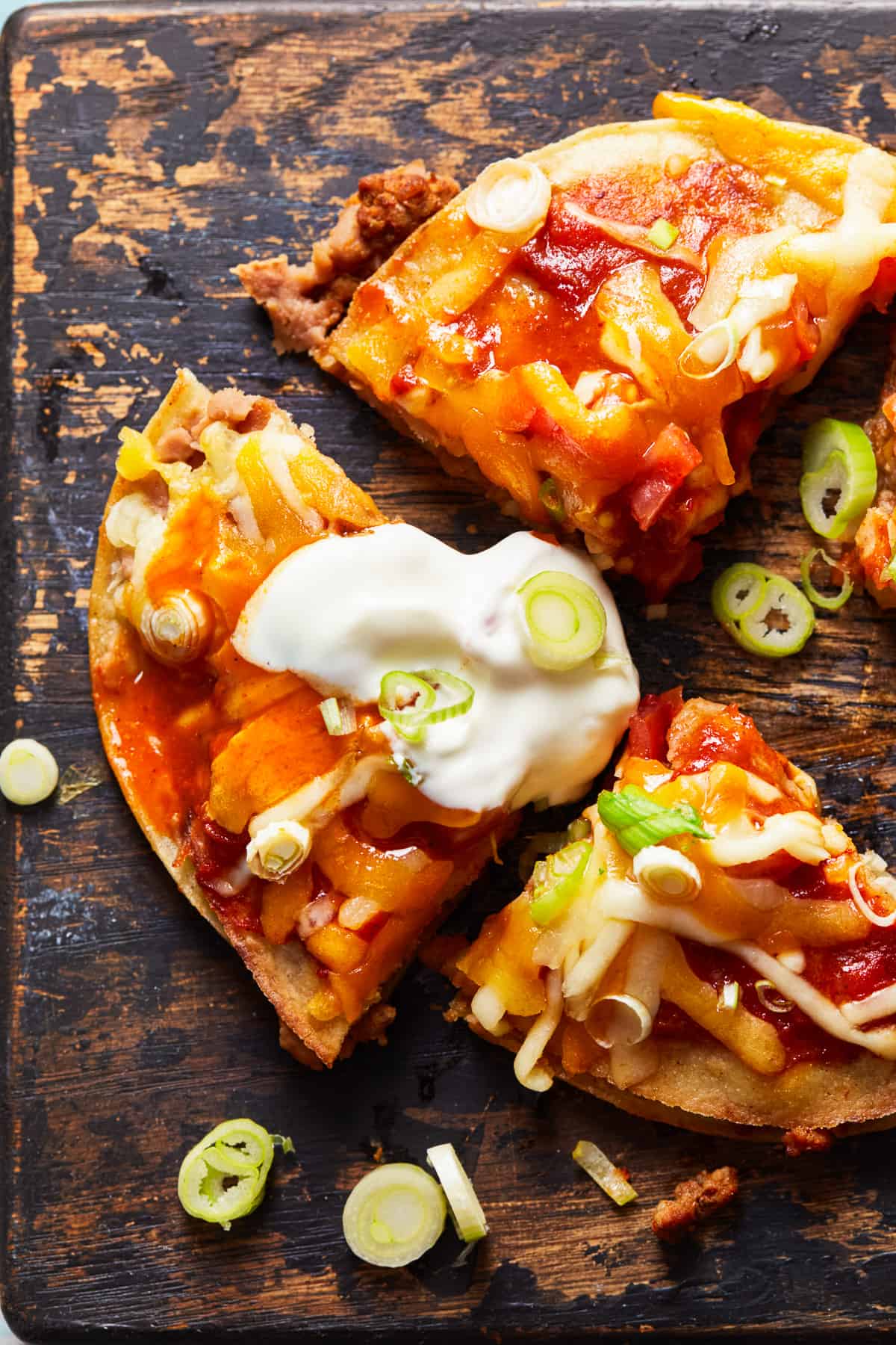 Mexican pizza cut into quarters with a dollop of sour cream. - 12