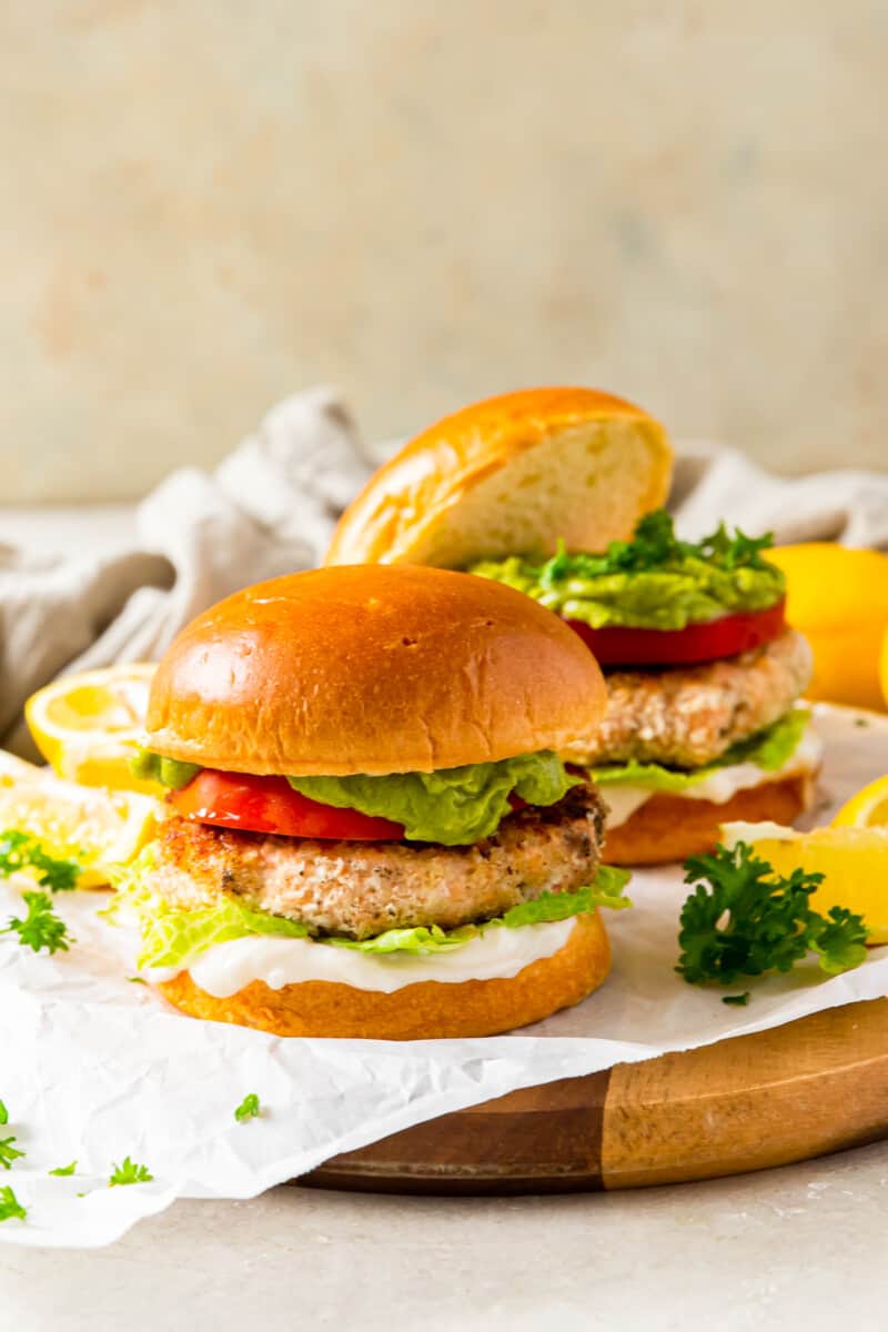 salmon burger on a bun topped with tomato, lettuce, guacamole