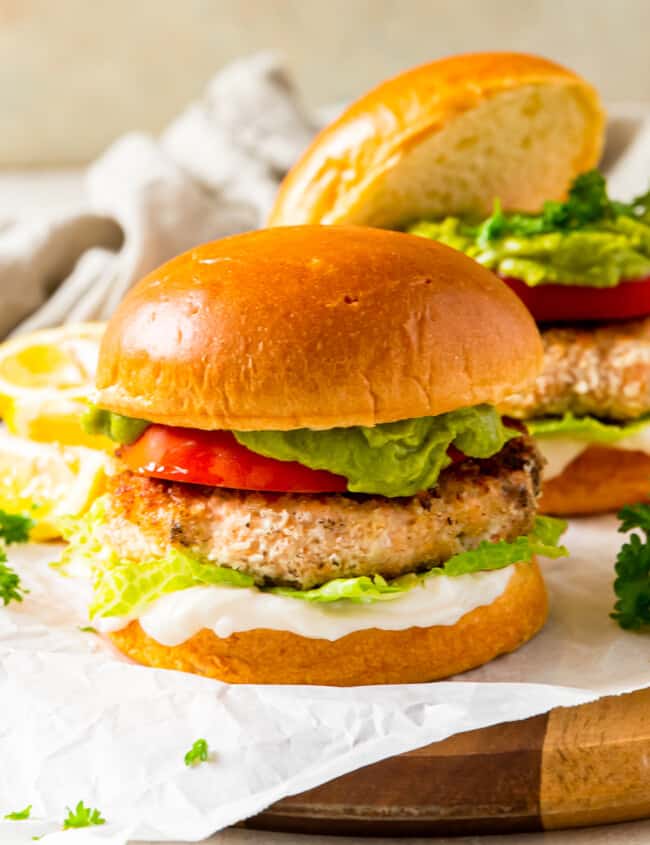 salmon burger on a bun topped with tomato, lettuce, guacamole