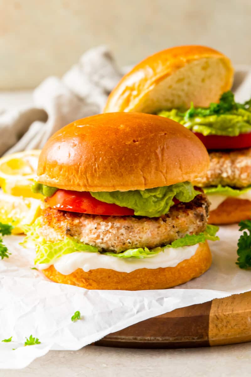 salmon burger on a bun topped with tomato, lettuce, guacamole