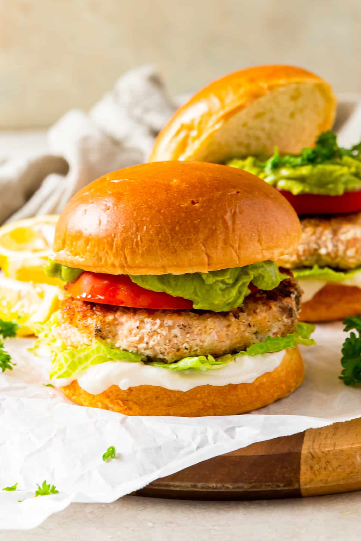 salmon burger on a bun topped with tomato, lettuce, guacamole