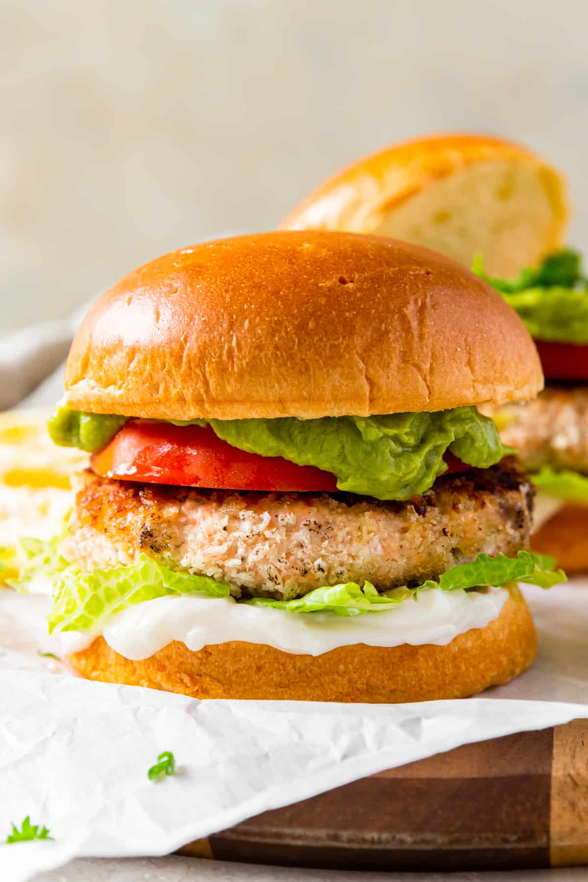 salmon burger on a bun topped with tomato, lettuce, guacamole