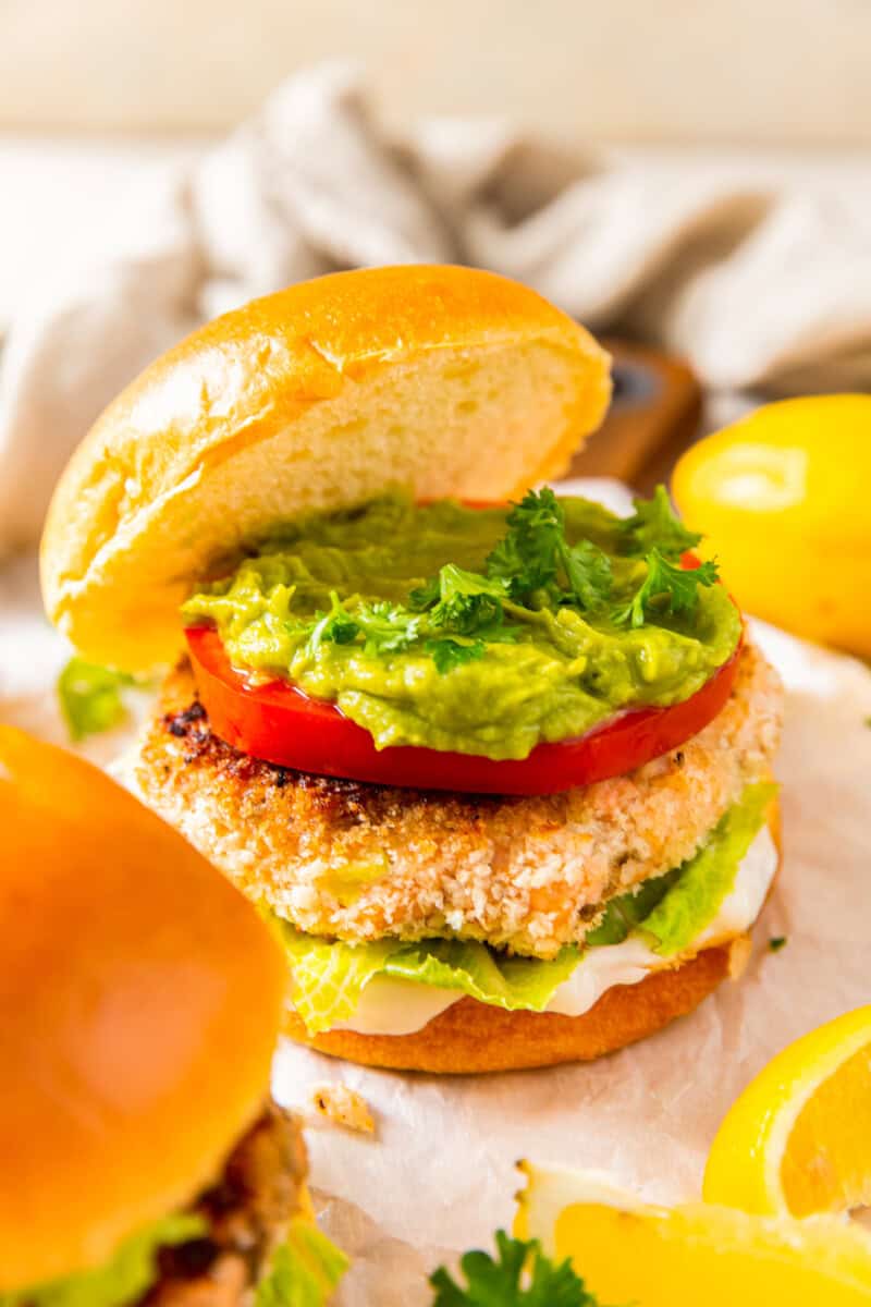 salmon burger on a bun topped with tomato, lettuce, guacamole